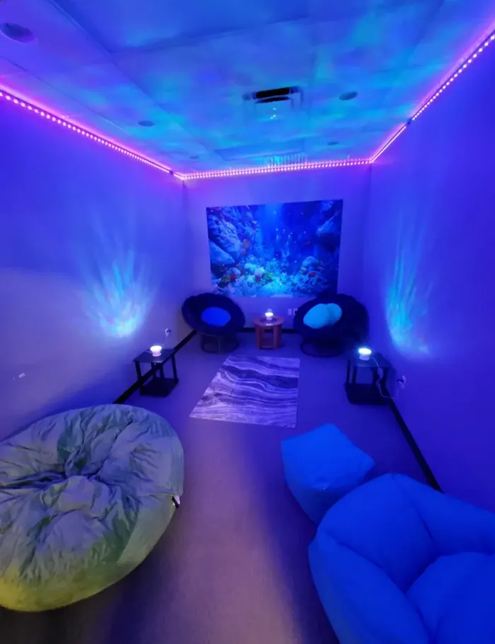 Calming sensory room with mood lighting and seating for client relaxation at Bridges Community Support Services